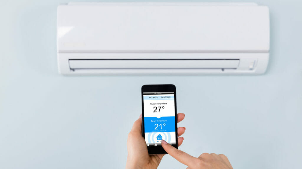 A hand using a remote control to manage an air conditioning unit, symbolizing the enhancement of AC cooling efficiency
