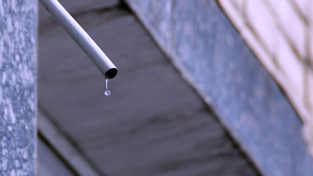 An AC drain line, distinguished by a visible drop of water at its end, illustrating the role it plays in transporting condensation away from the AC unit. This image underscores the importance of regular maintenance to ensure optimal AC performance and prevent water damage.