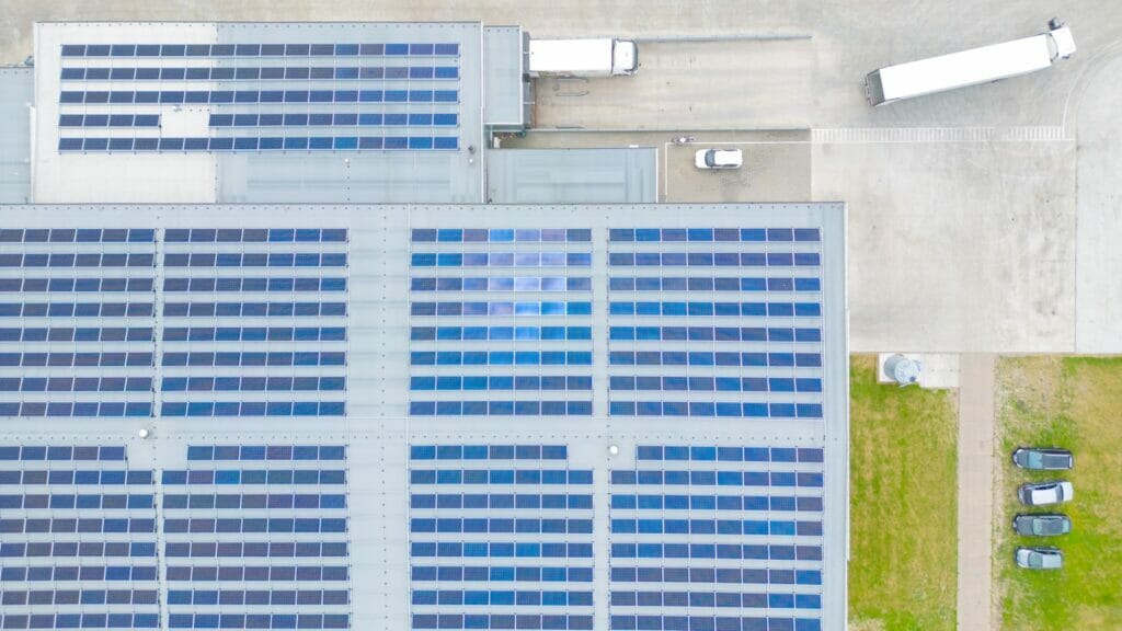 Aerial view of photovoltaic solar cells on a warehouse roof, captured by drone from above.