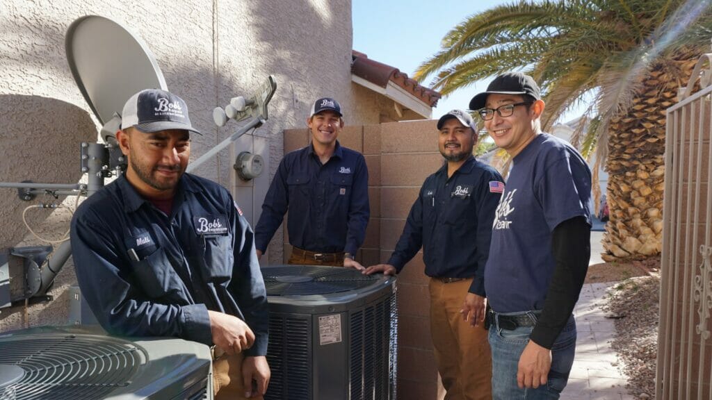 Team of Bob's Repair technicians in Paradise, NV, performing maintenance on outdoor AC units to extend their lifespan, set against the backdrop of a local home and a palm tree.