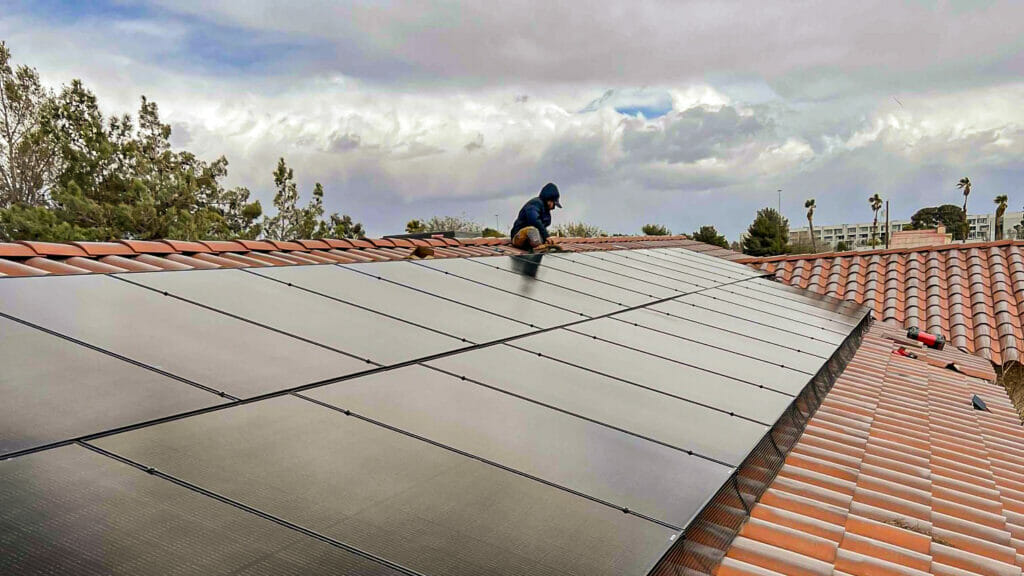 Technician fixing a solar panel on a clay roof, exemplifying the expert solar panel repair services offered by Bob's Repair.