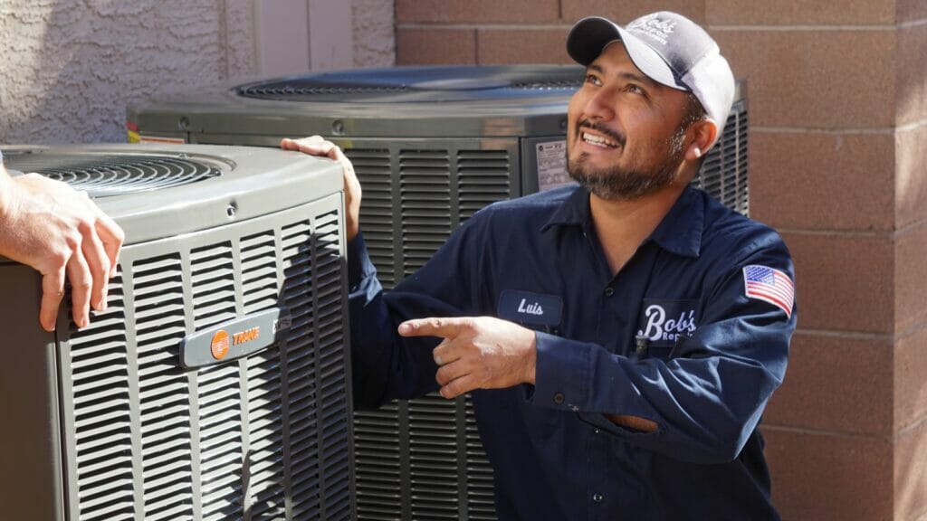 Bob's Repair technician standing beside a newly installed modern energy-efficient AC unit in a Las Vegas home.