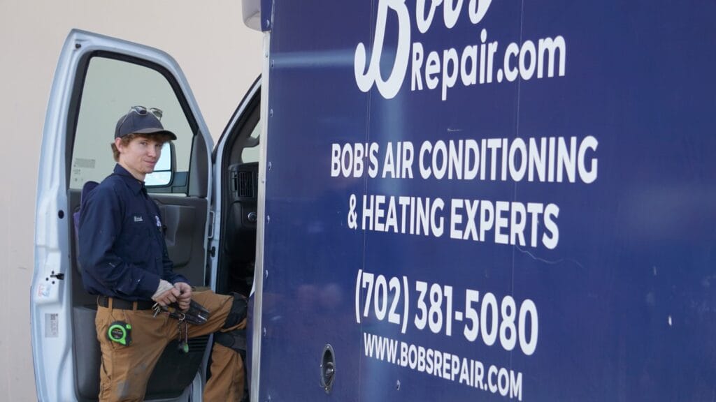 Bob's Repair technician standing next to a company vehicle, preparing tools for an AC installation.
