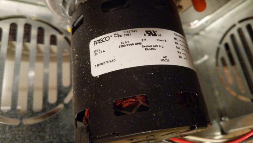 A close-up of an HVAC blower motor with a Fasco label, showing technical specifications including voltage, amperage, and capacitor rating.