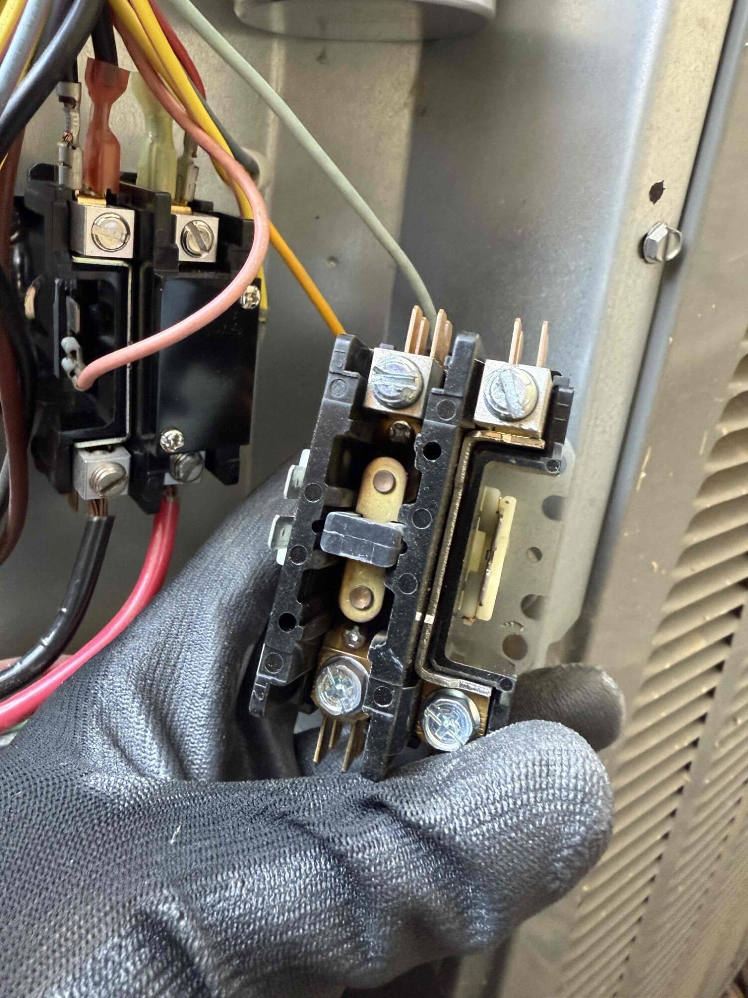 echnician showing a pitted contactor removed from condenser unit