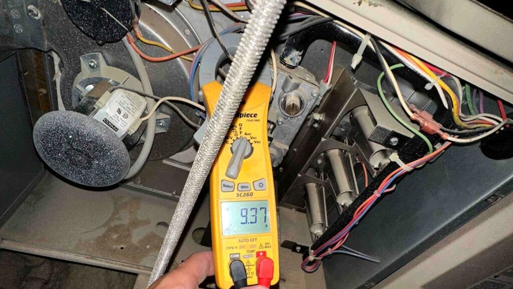 Multimeter showing a 9.37 amp draw reading during HVAC blower motor testing inside a furnace cabinet.