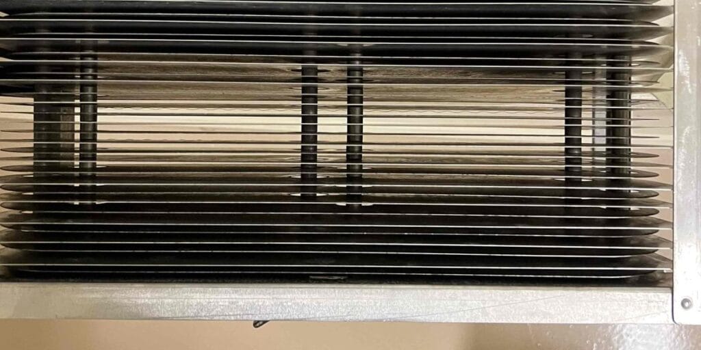 A dark vent grille with slats visible from below, no visible dust or moisture on the metal.