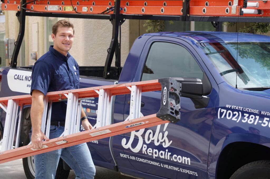 A Bob's Repair technician carries a ladder to his branded truck, ready to help a homeowner dealing with AC water damage in Las Vegas, Summerlin, and Henderson.