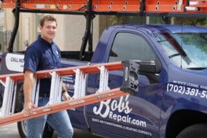 A Bob's Repair technician carries a ladder to his branded truck, ready to help a homeowner dealing with AC water damage in Las Vegas, Summerlin, and Henderson.