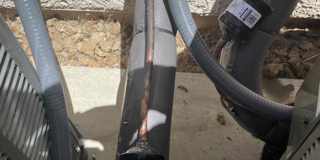 A close-up of a refrigerant line and a wired electrical component on an outdoor AC unit, the kind of wiring issue that often leads to aircon compressor noise in Summerlin and Henderson homes.