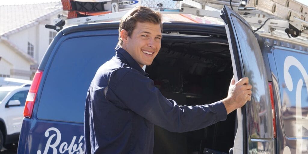 A smiling HVAC technician from Bob's Repair stands by his service van, ready to provide AC repair and maintenance services in Las Vegas.